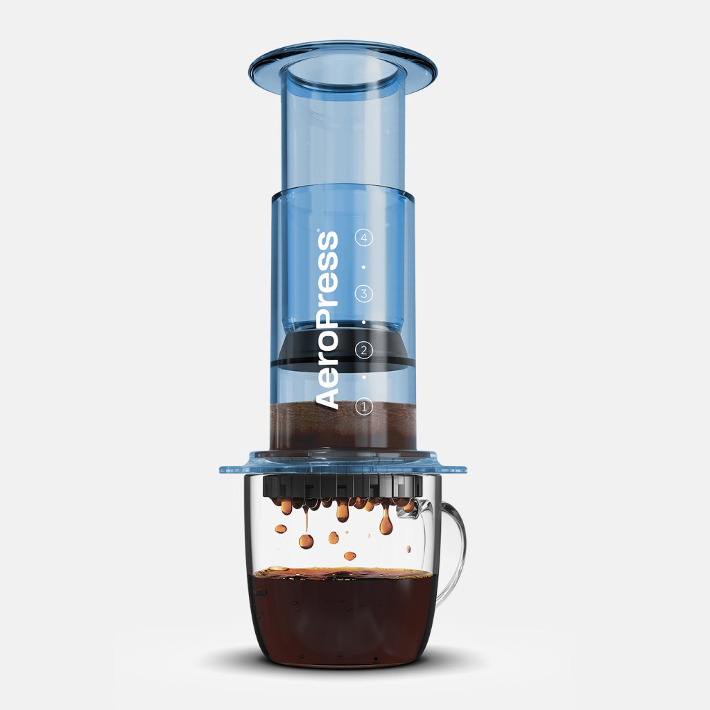 Translucent Blue AeroPress with measurement marks and coffee dripping into a glass carafe