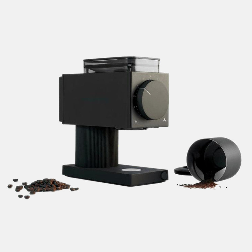 Ode Gen 2 grinder in matte black with a large front dial and top hopper, surrounded by beans and ground coffee.