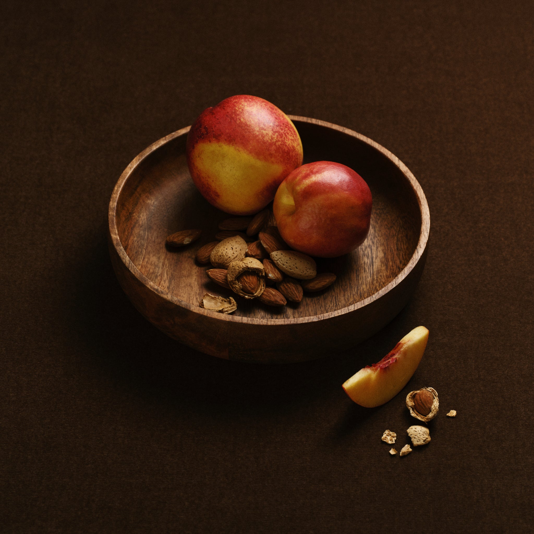 Wooden bowl of Nectarines and almonds in and out of shell.