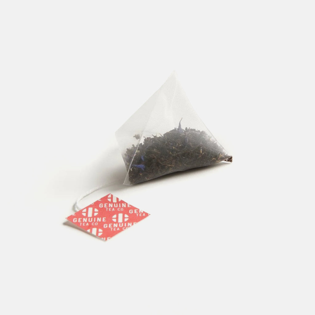 Pyramid tea bag with loose black tea and a red Genuine Tea Co tag on a white background.