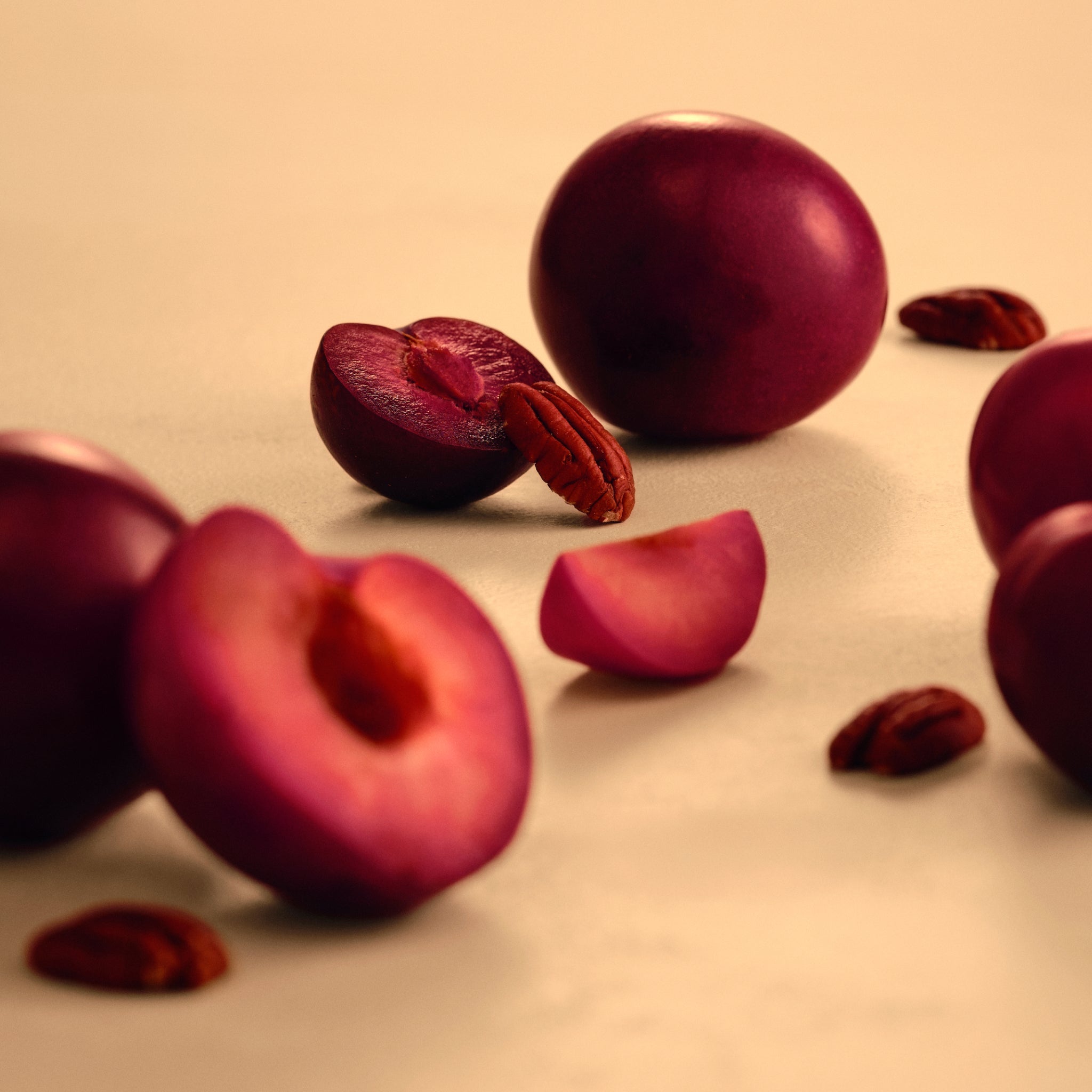Close up of whole and sliced plums, with pecan nuts