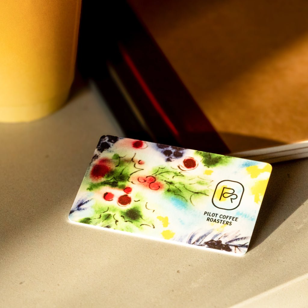 Pilot Coffee Roasters gift card with colorful floral artwork on a light surface.