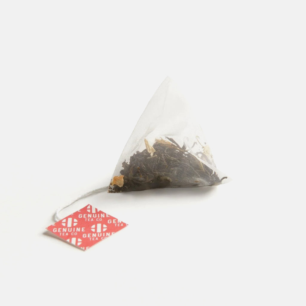 Pyramid tea bag with red Genuine Tea Co tag containing Premium Jasmine green tea.