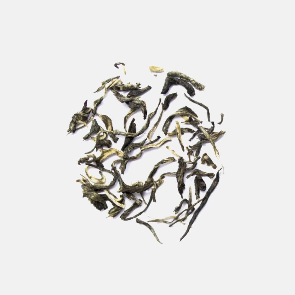 Loose jasmine green tea leaves arranged in a circular shape on a white background.